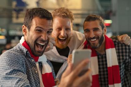 Three men looking at a mobile phone and laughing