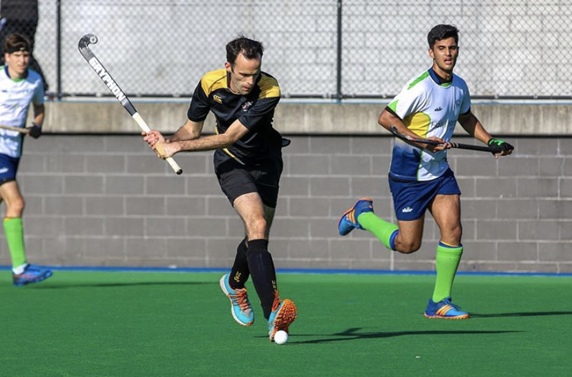 A UNSW men's hockey player hits the ball