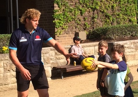 Ned Hanigan teaches some rugby passing skills to a young fan.