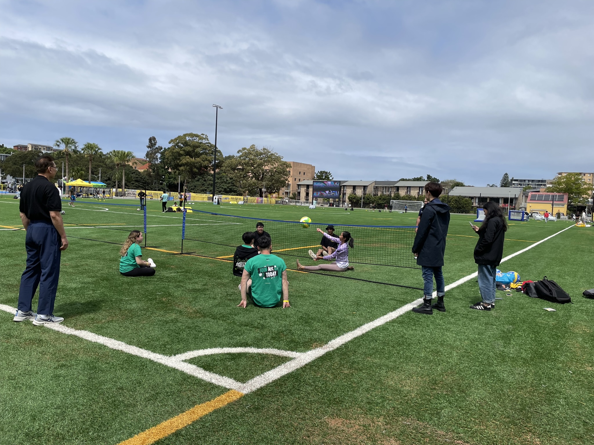 Students playing sitting volleyball on the synthetic field