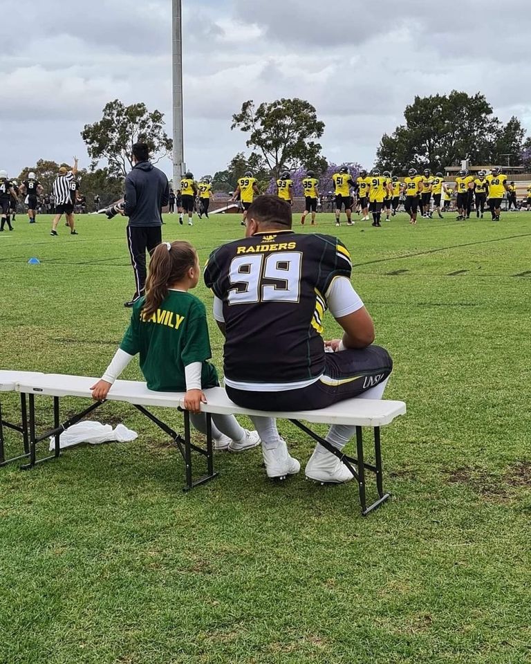 Raiders player sitting with a small child on a bench