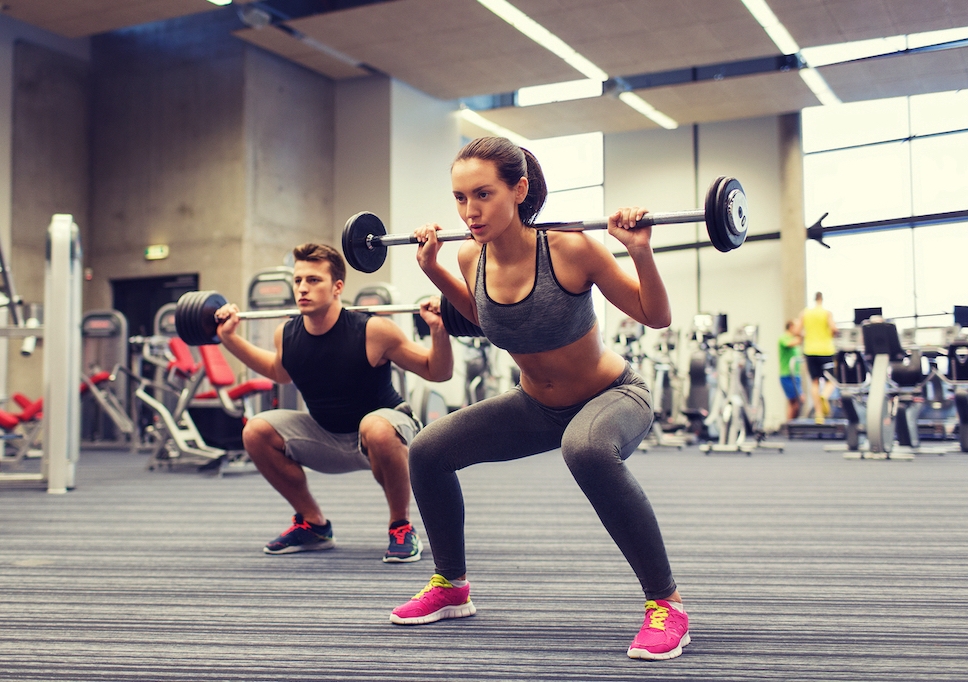 A woman and a man lifting weights in a gym