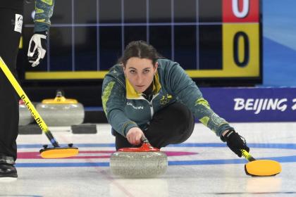 An olympic curler crouches low to the ground