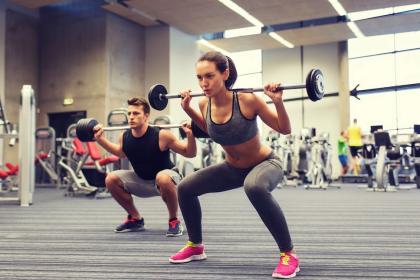 A woman and a man lifting weights in a gym